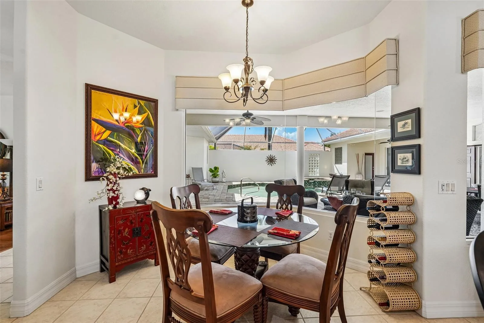 Sunlit breakfast nook featuring tile flooring, a decorative chandelier and floor-to-ceiling aquarium glass windows offering seamless, unobstructed views of the screened pool and lanai