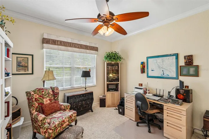 Versatile home office or guest bedroom featuring plush carpeting, Murphy Bed, crown molding, a wood-blade ceiling fan and a large window providing ample natural light