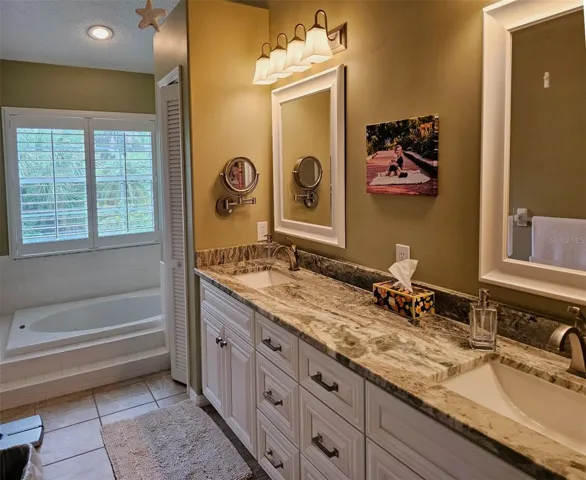 The primary bath features a soaking bathtub, dual vanieties, granite counters and a linen closet