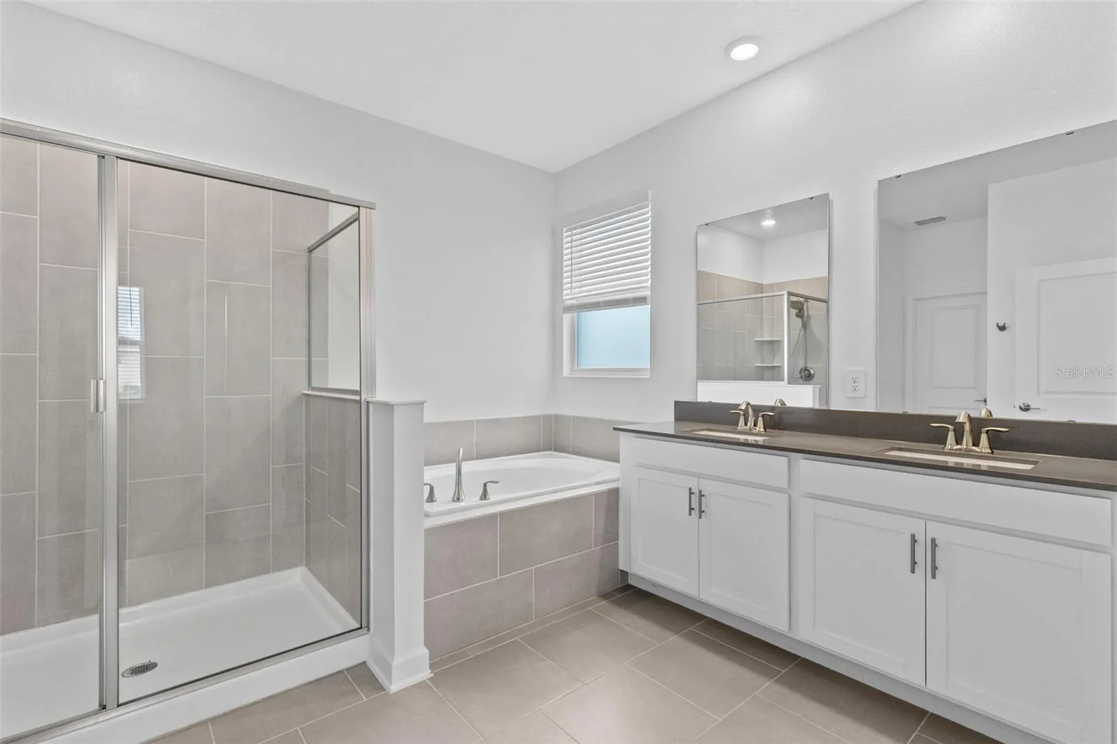 Tucked away at the rear of the home, the primary suite offers a generous walk in closet and a spacious private bathroom complete with quartz countertops, dual sinks, a soaking tub and separate shower. Direct access from the primary suite into the laundry room adds another layer of everyday convenience.