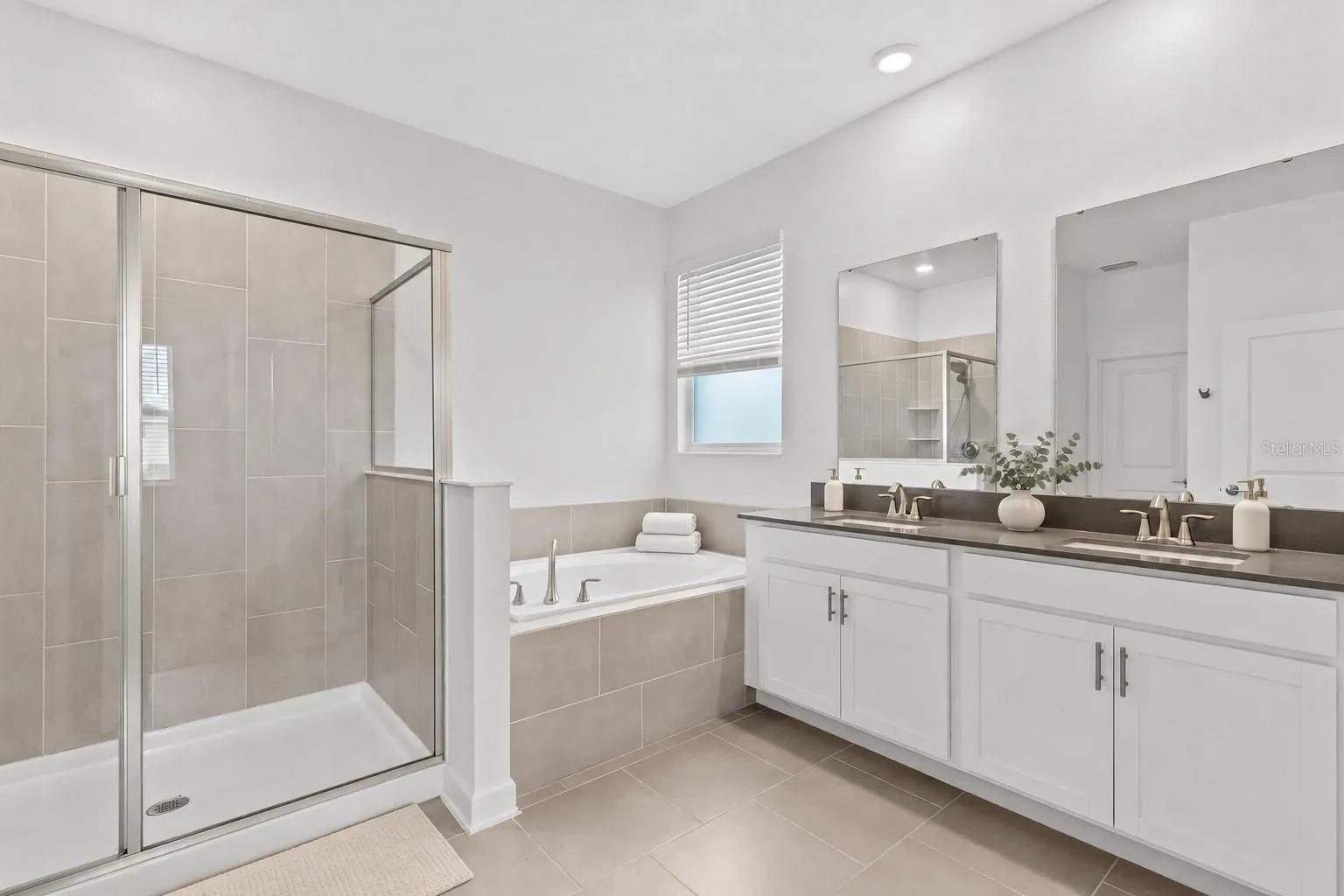 Tucked away at the rear of the home, the primary suite offers a generous walk in closet and a spacious private bathroom complete with quartz countertops, dual sinks, a soaking tub and separate shower. Direct access from the primary suite into the laundry room adds another layer of everyday convenience.