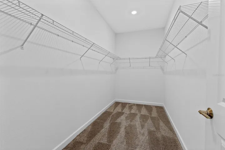 Tucked away at the rear of the home, the primary suite offers a generous walk in closet and a spacious private bathroom complete with quartz countertops, dual sinks, a soaking tub and separate shower. Direct access from the primary suite into the laundry room adds another layer of everyday convenience.
