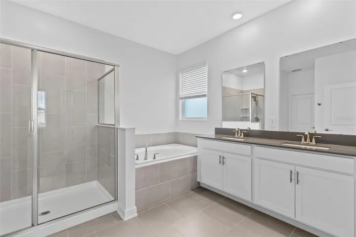 Tucked away at the rear of the home, the primary suite offers a generous walk in closet and a spacious private bathroom complete with quartz countertops, dual sinks, a soaking tub and separate shower. Direct access from the primary suite into the laundry room adds another layer of everyday convenience.