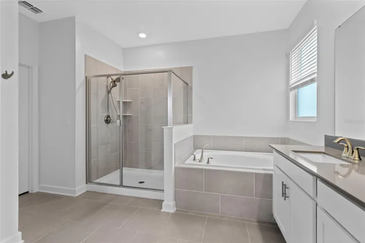 Tucked away at the rear of the home, the primary suite offers a generous walk in closet and a spacious private bathroom complete with quartz countertops, dual sinks, a soaking tub and separate shower. Direct access from the primary suite into the laundry room adds another layer of everyday convenience.
