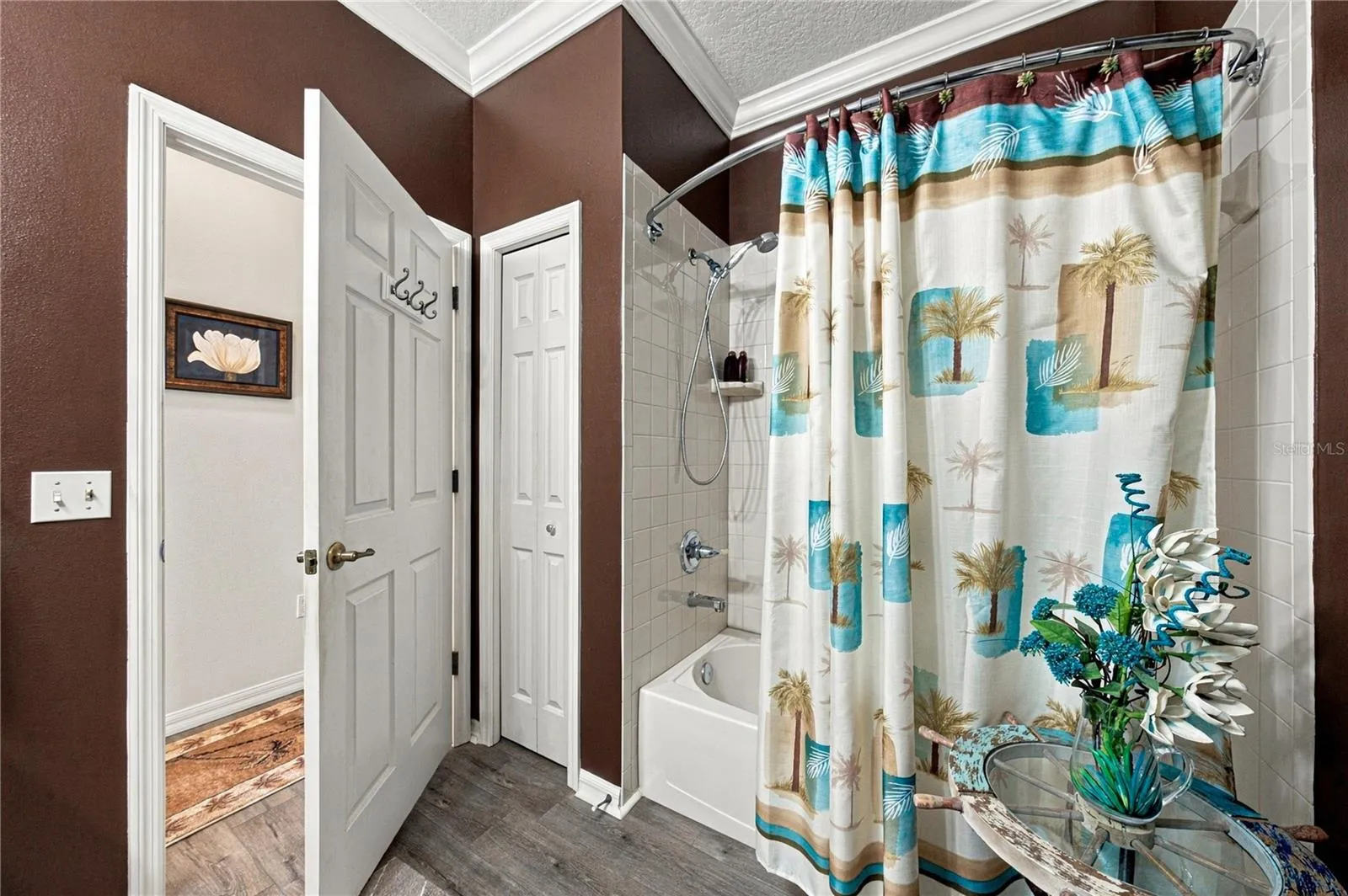 The guest bath has a linen closet and a combination shower and tub with a ceramic tile surround.