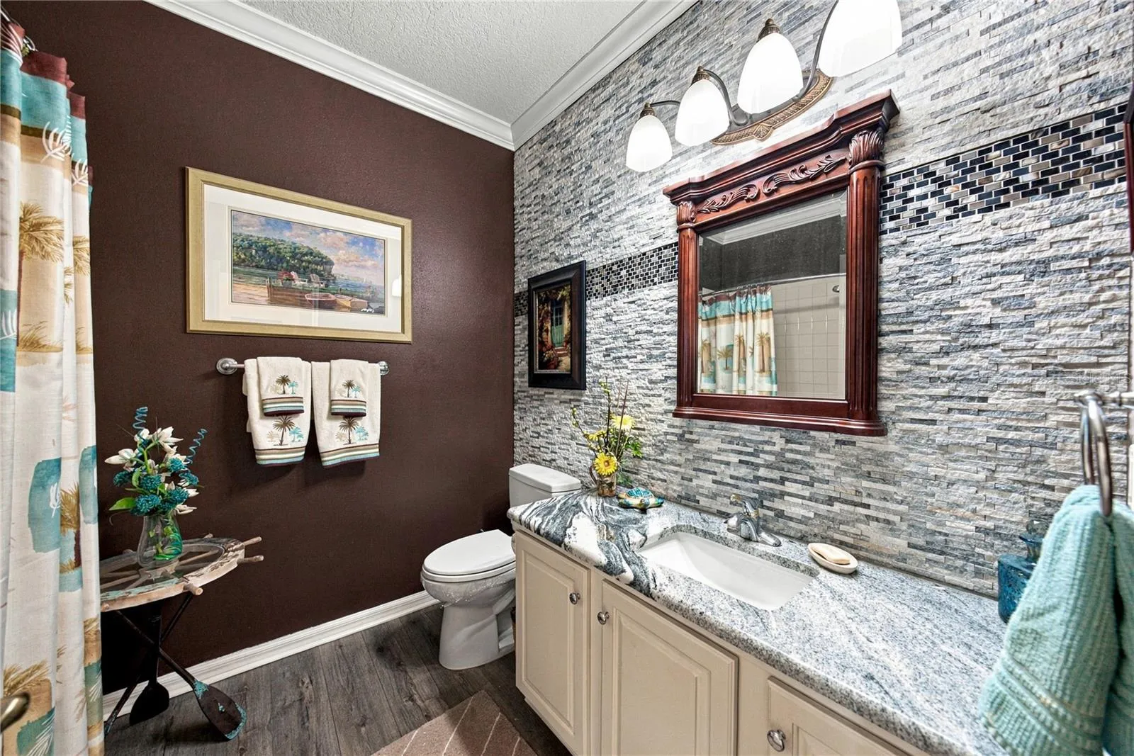 The recently remodeled guest bath has an elongated stool, stone counters, upgraded plumbing and lighting fixtures. The stone wall with accents adds to the richness of this space.