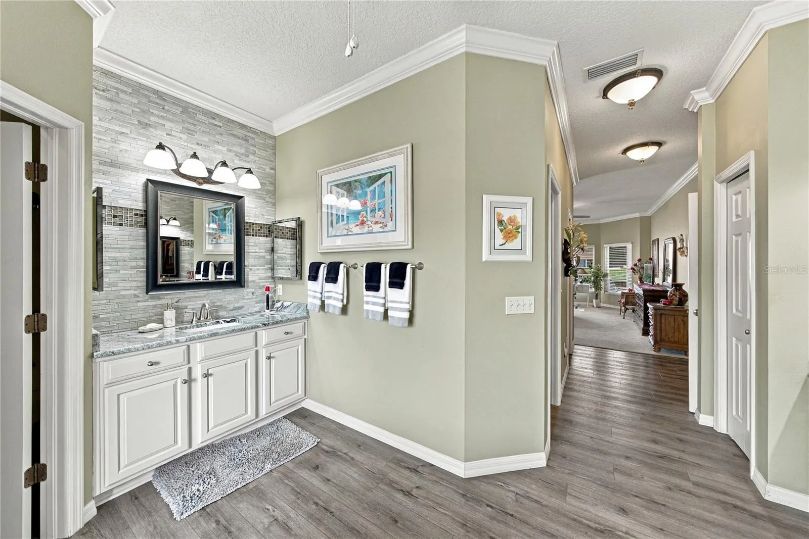 The west vanity also has stone countertops, stone wall with accents, and upgraded fixtures.