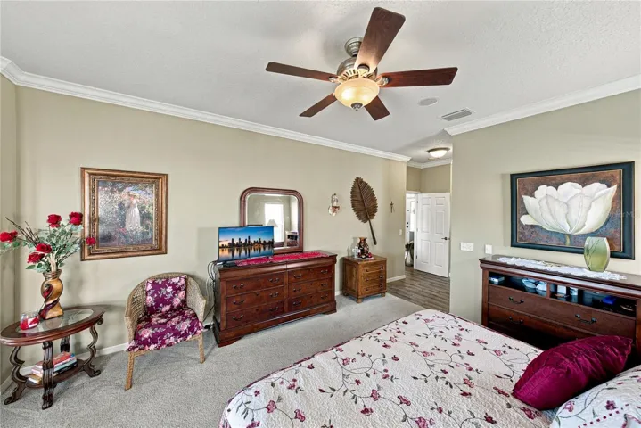 The primary bedroom has a designer ceiling fan with light, crown molding, and quality carpeting.