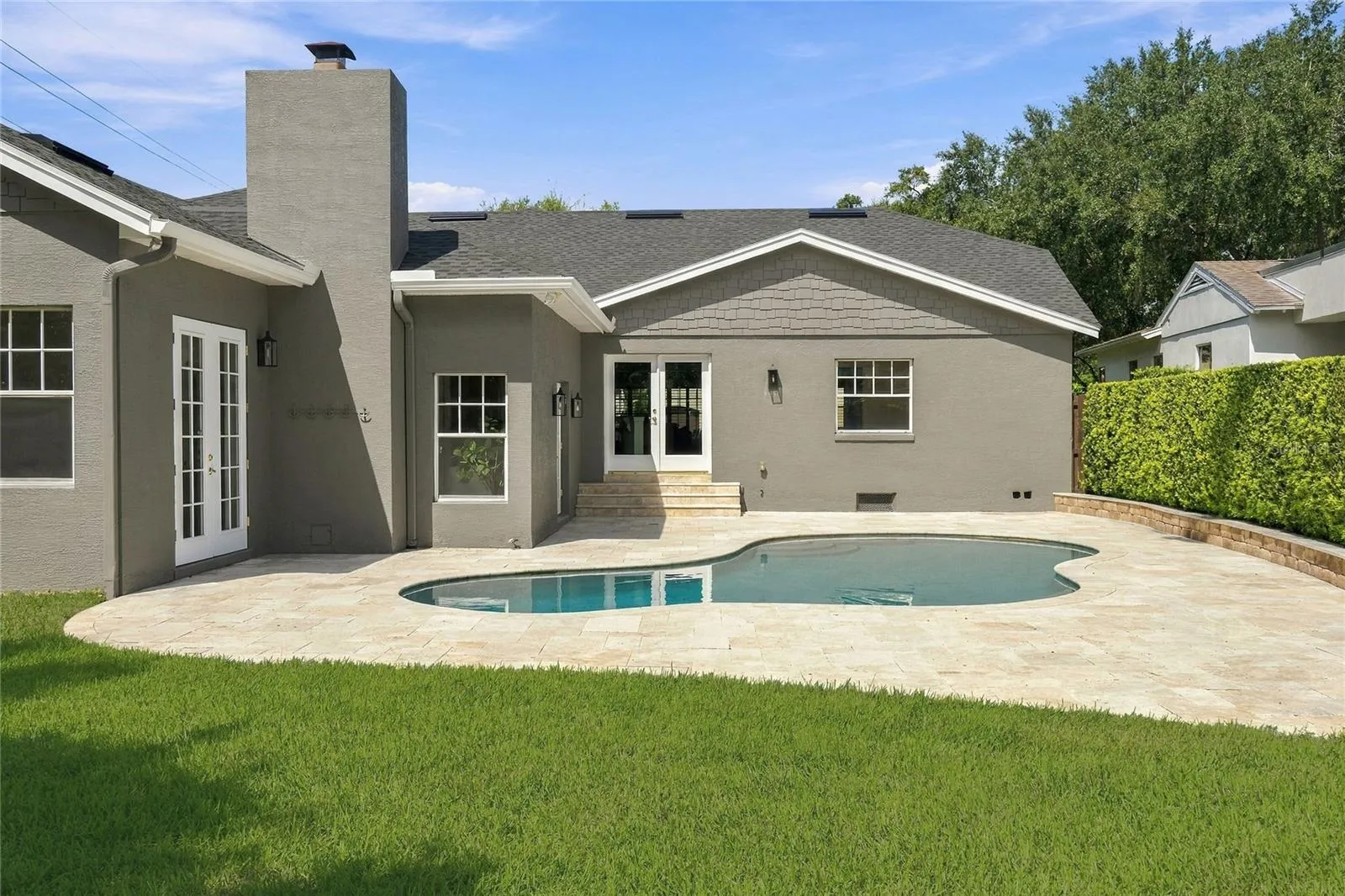 Back of the house has been designed around the pool, with travertine decking wrapping the freeform design & multiple sets of French doors creating a natural connection from the interior.