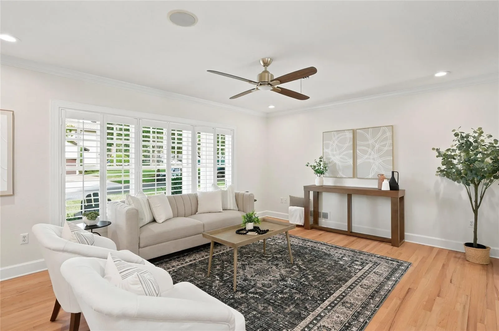 Living space with big front windows & shutters bringing in lots of light