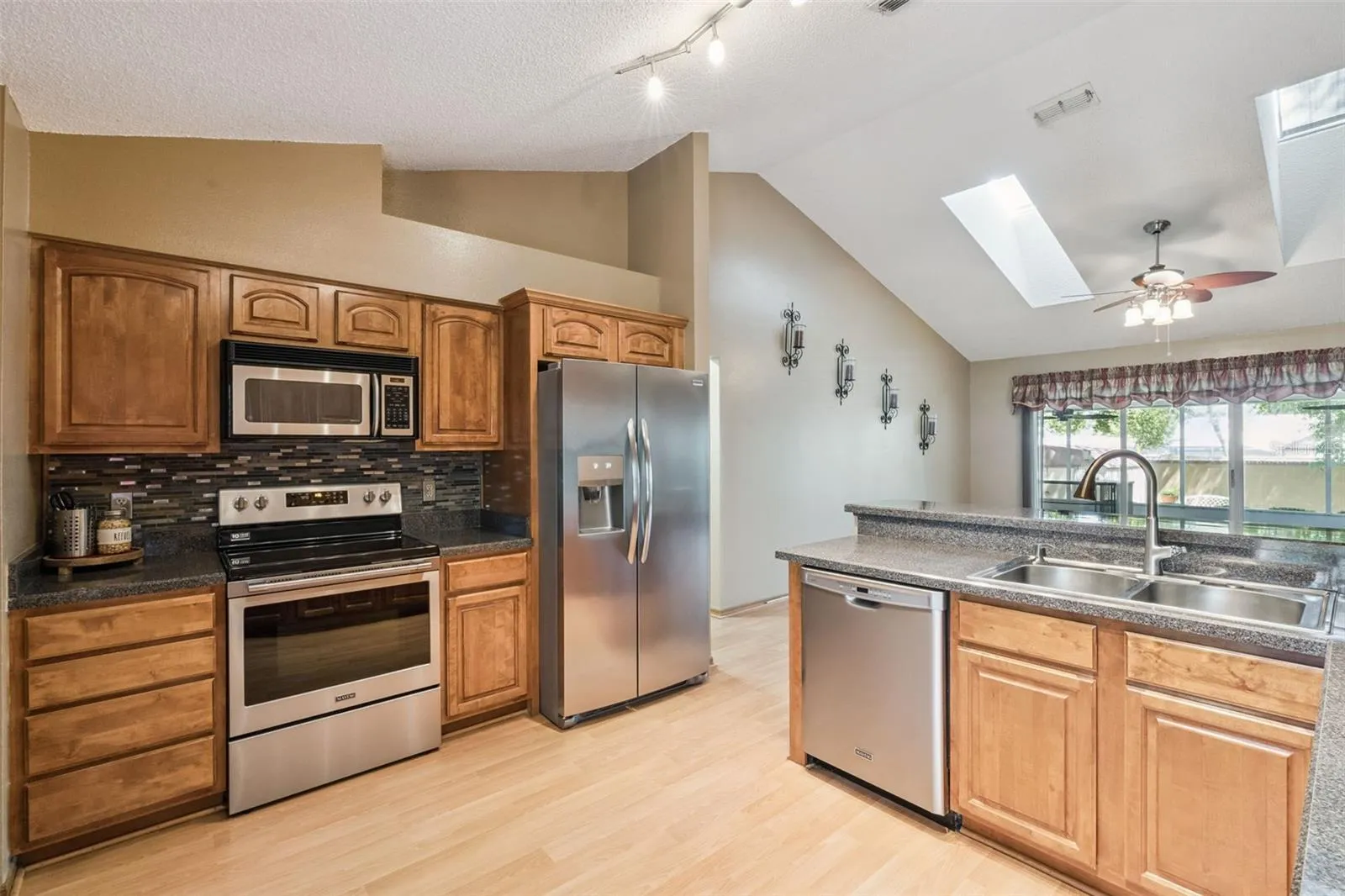 Updated kitchen featuring stainless-steel appliances, tiled backsplash and beautiful solid wood cabinetry.