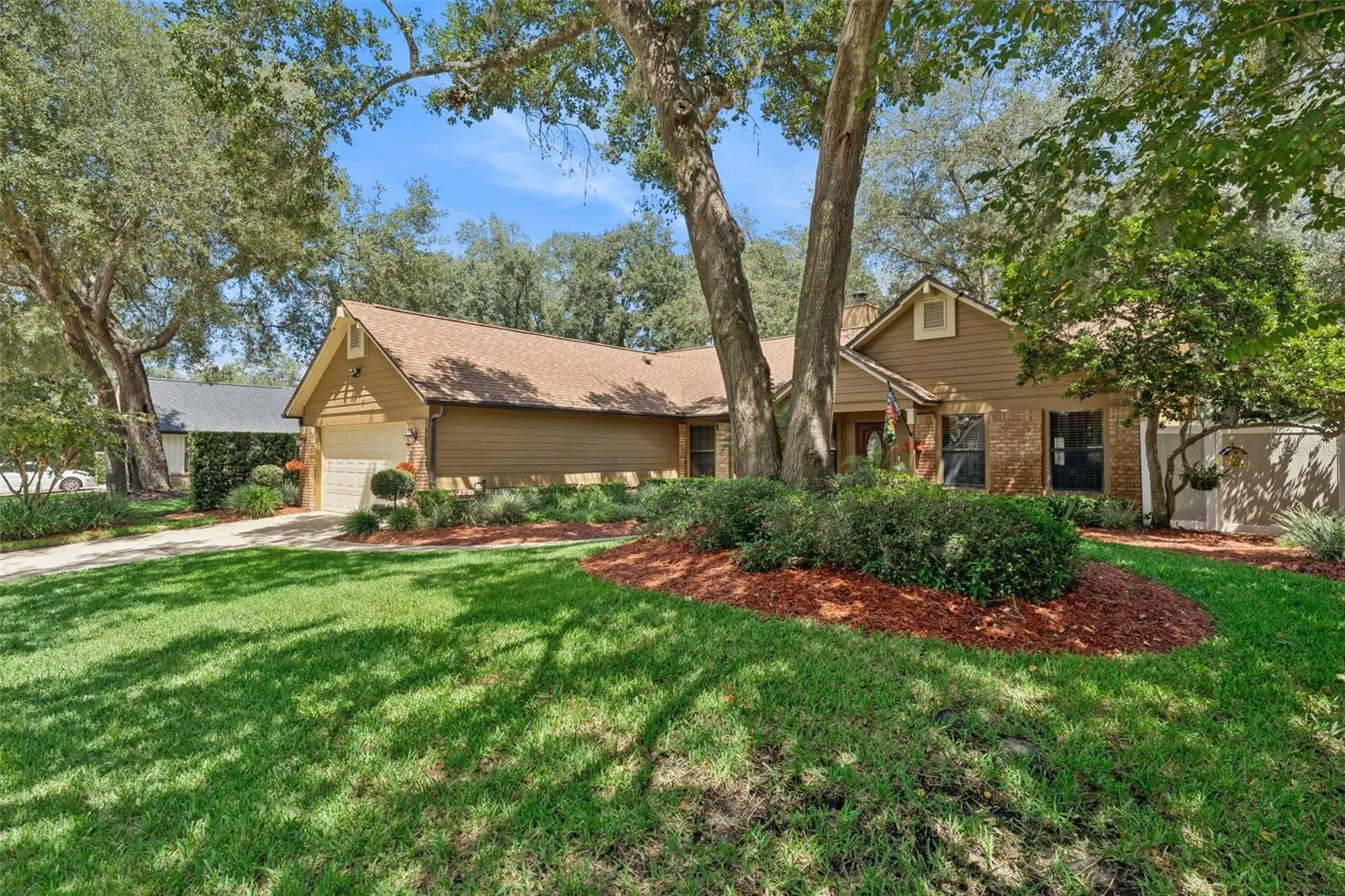 Beautiful street view showcasing the spacious front yard, mature oaks and lush landscaping.