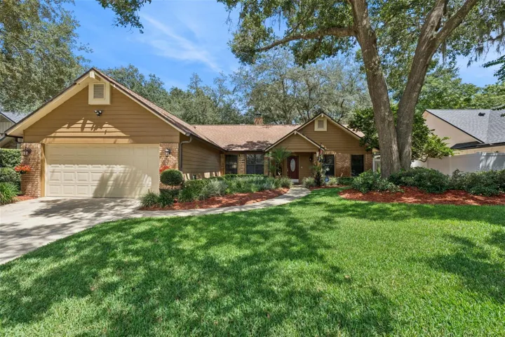 Beautiful curb appeal beneath majestic oaks, with lush landscaping and a spacious two-car garage.