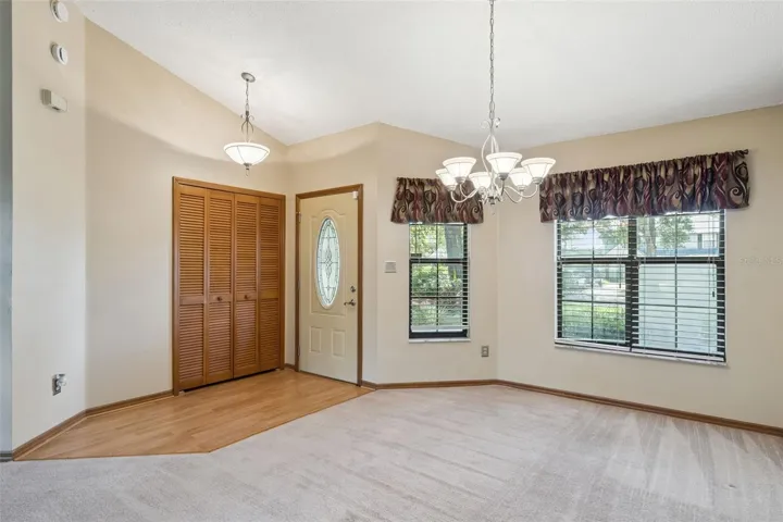 A welcoming front foyer flows into the spacious dining area, where vaulted ceilings and abundant natural light create an open, inviting first impression.