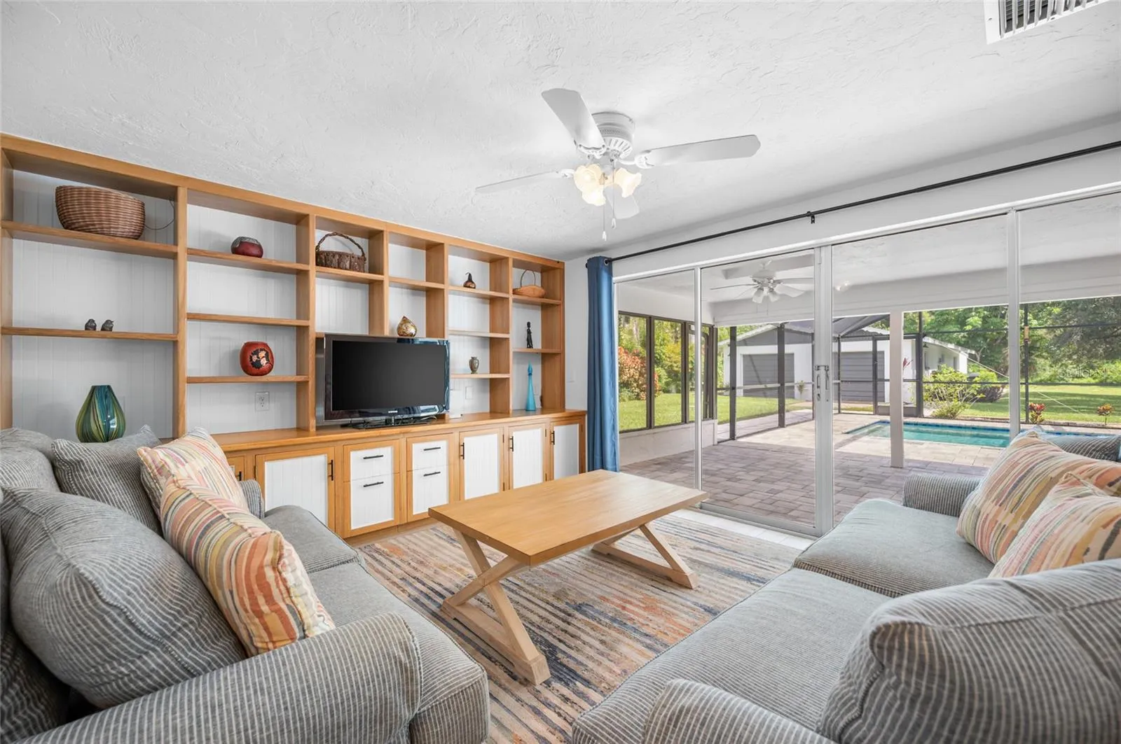 Living room with built in shelving and sliders opening to the lanai