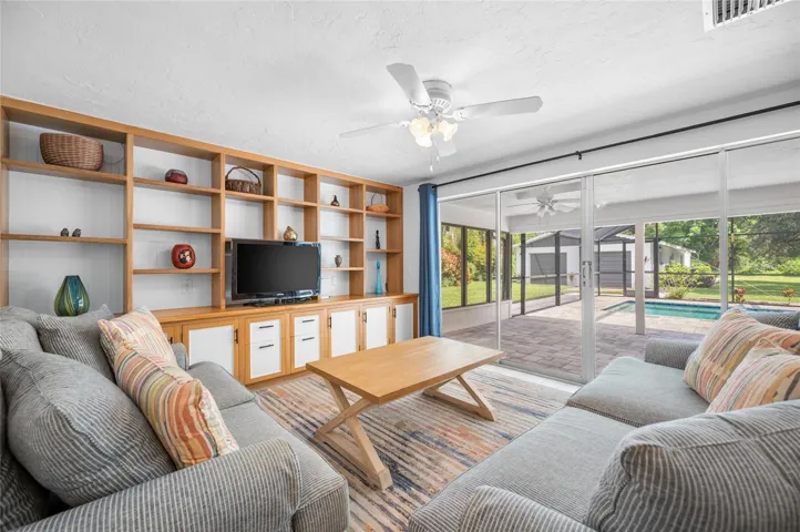 Living room with built in shelving and sliders opening to the lanai