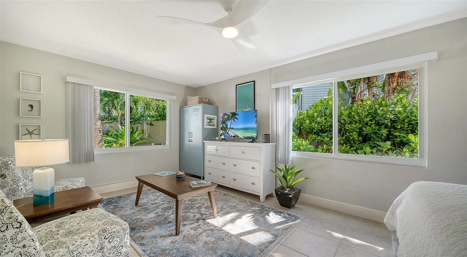 Bright guest bedroom with multiple windows overlooking the lush landscaping.