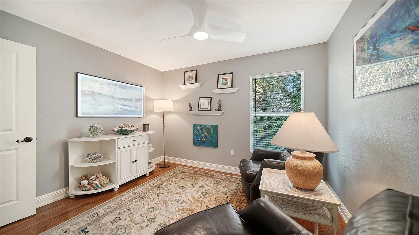 Bright guest bedroom or flexible space with hardwood flooring.