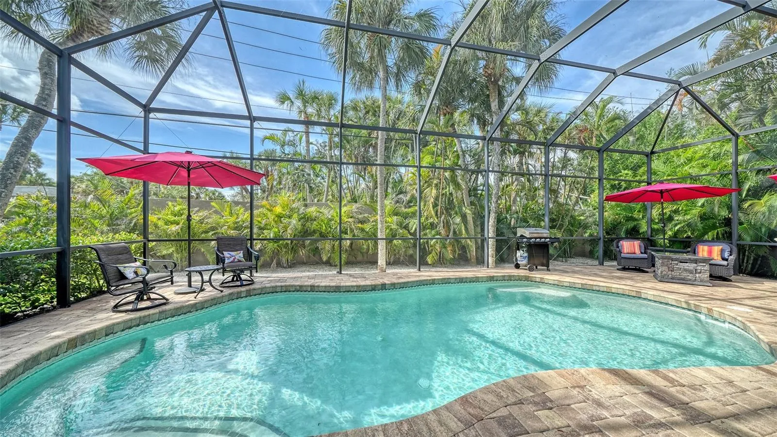 Heated free-form saltwater pool surrounded by tropical landscaping and privacy screening.