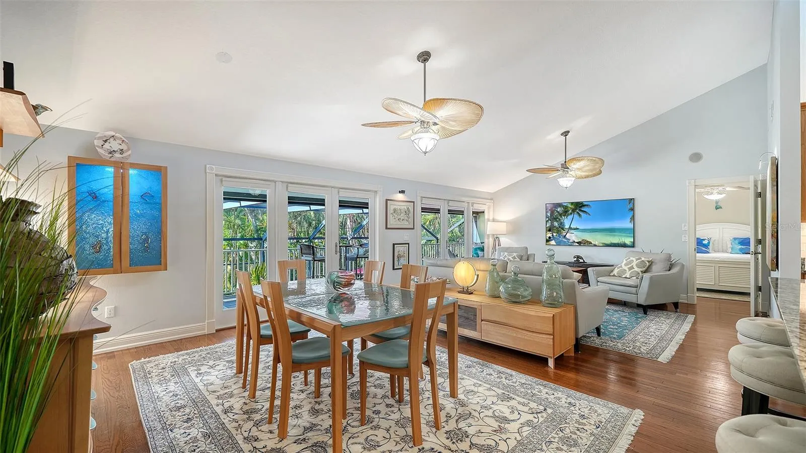 Open concept dining and living areas with hardwood floors and vaulted ceilings.