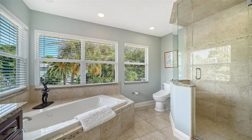 Spacious primary bath with jetted tub, separate shower and abundant natural light.