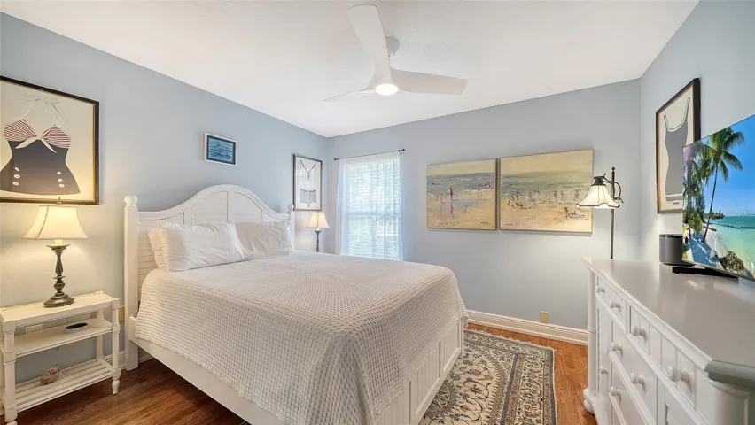 Comfortable guest bedroom with hardwood flooring and natural light.
