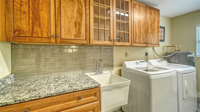 Convenient laundry room with cabinetry and new washer and dryer.