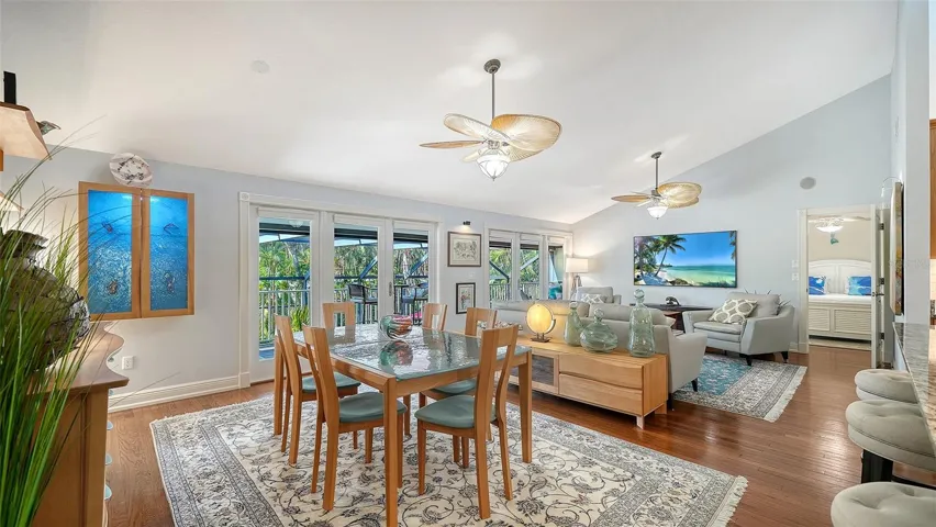 Open concept dining and living areas with hardwood floors and vaulted ceilings.