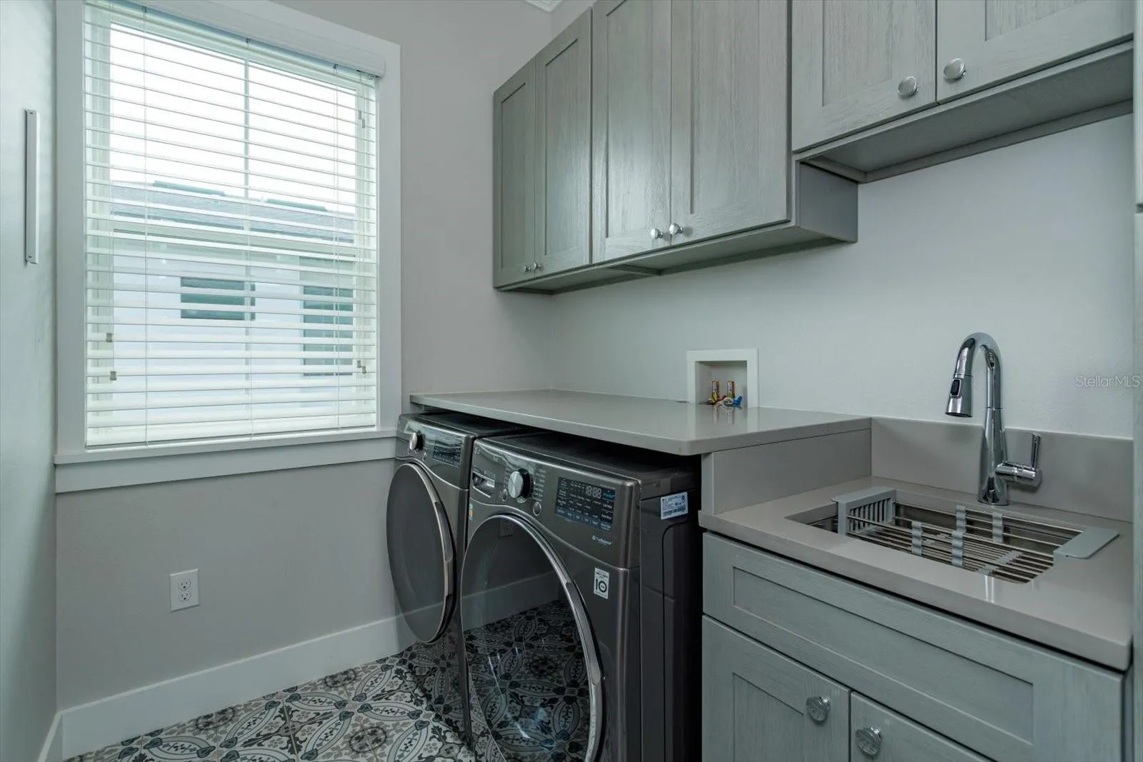 Second floor laundry room with utility sink and cabinetry