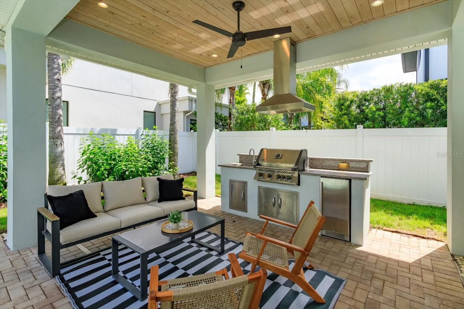 Brick paver lanai with summer kitchen with Napoleon gas grill, beverage fridge and vent hood