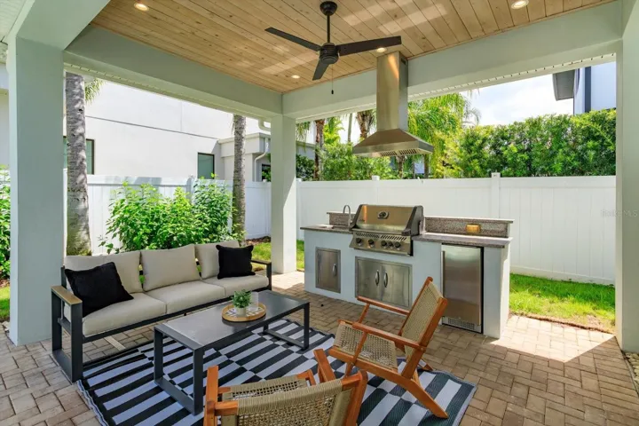 Brick paver lanai with summer kitchen with Napoleon gas grill, beverage fridge and vent hood