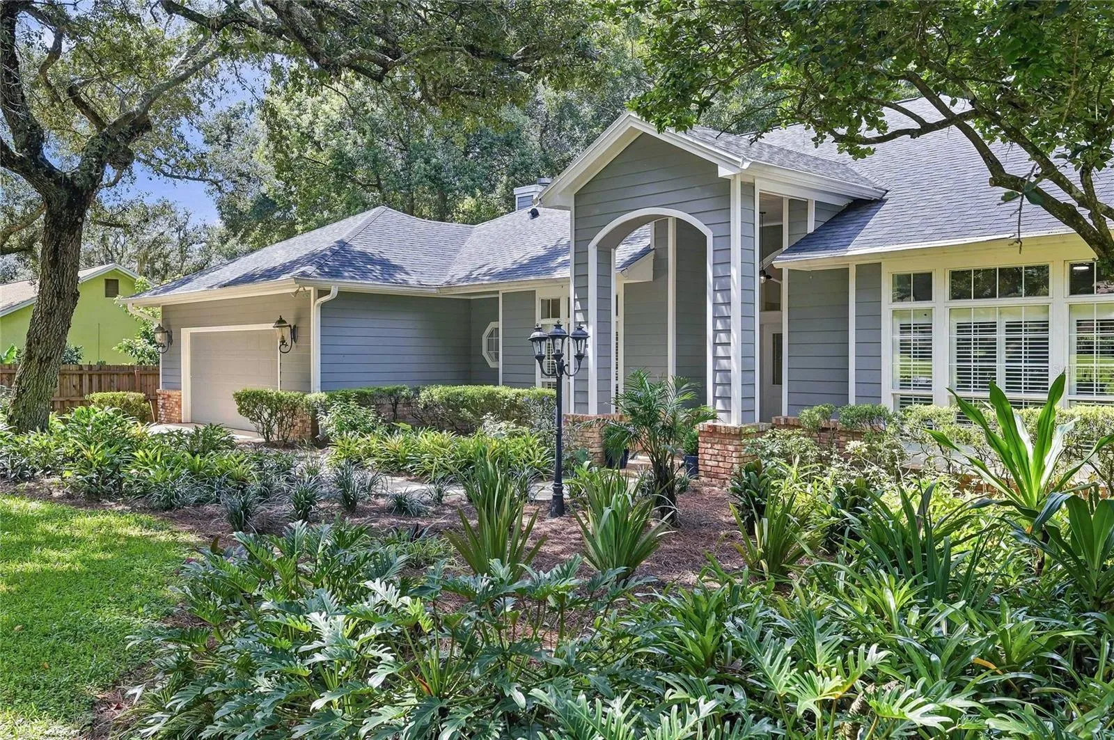 Magnificent canopy of mature oaks, surrounded by tropical landscaping and classic Southern charm.