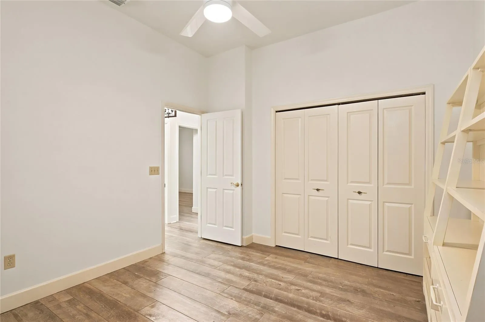 Bedroom 3 offers a comfortable, versatile retreat with high ceilings, wood-look flooring, a ceiling fan, and generous closet space