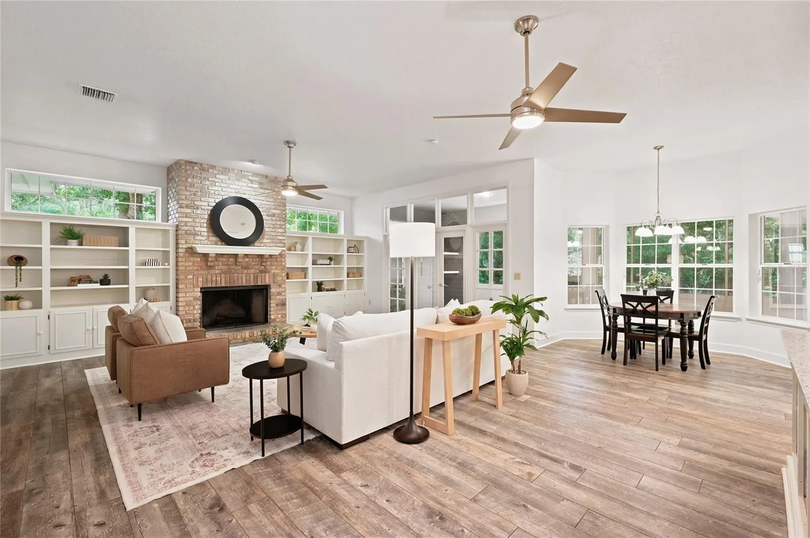 The expansive family room features a classic brick fireplace with custom built-ins and flows effortlessly into the sun-filled breakfast area.