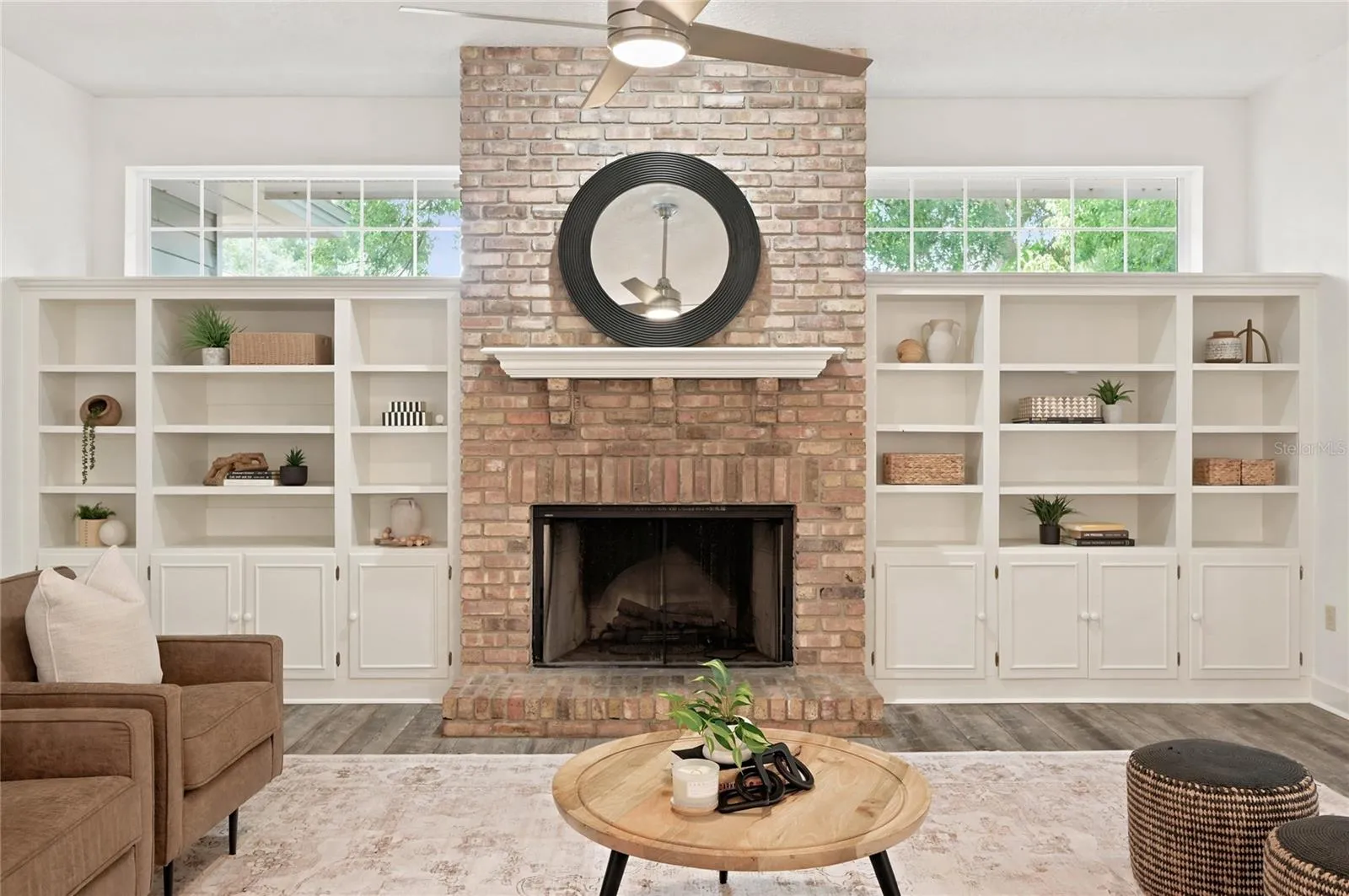 A floor to ceiling brick fireplace serves as an elegant focal point, surrounded by custom built-ins that add character, balance, and architectural interest to the room.