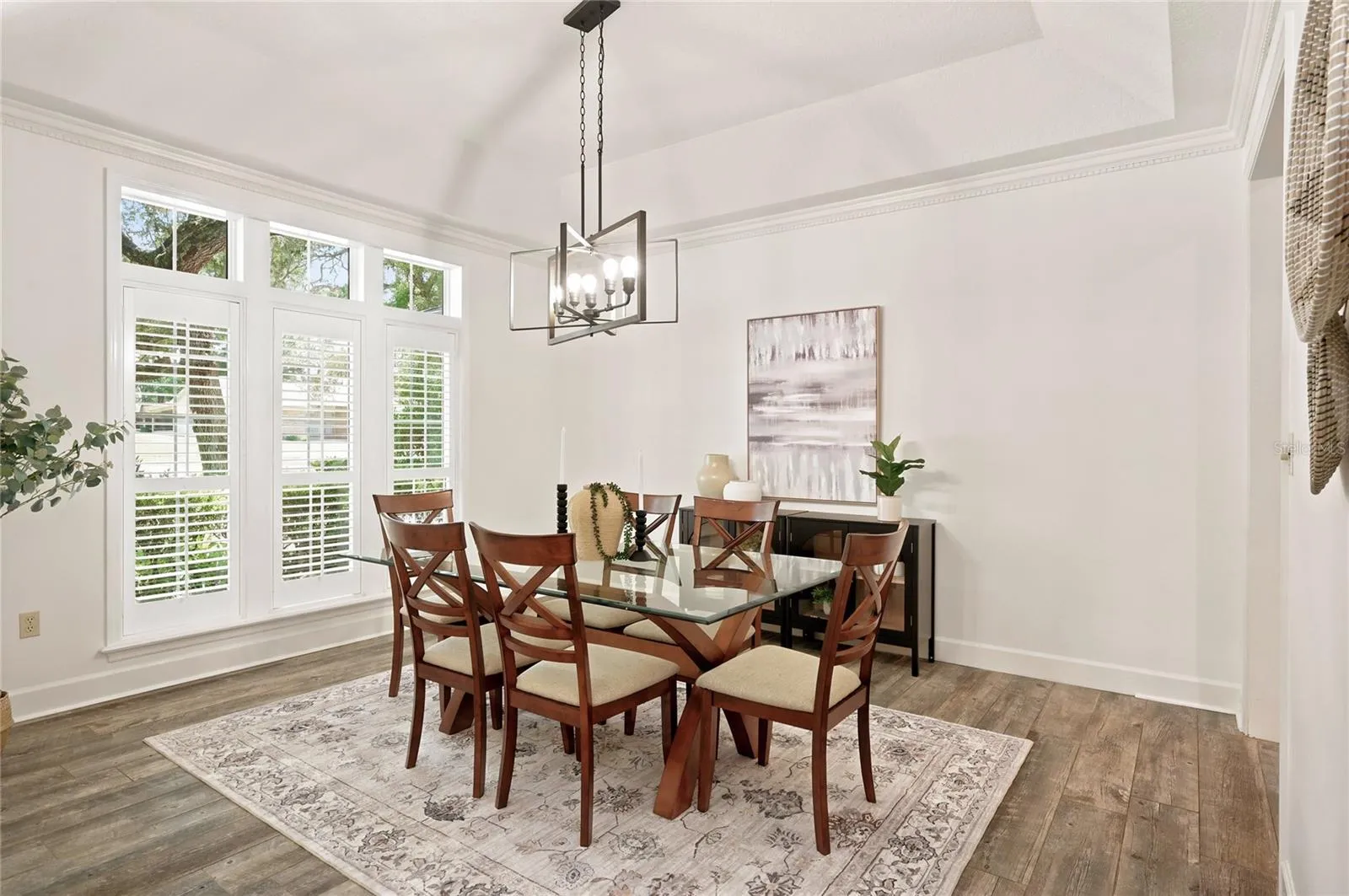 An spacious dining room features high ceilings, large scale windows, crown molding, and a contemporary chandelier, creating a beautiful setting for entertaining.