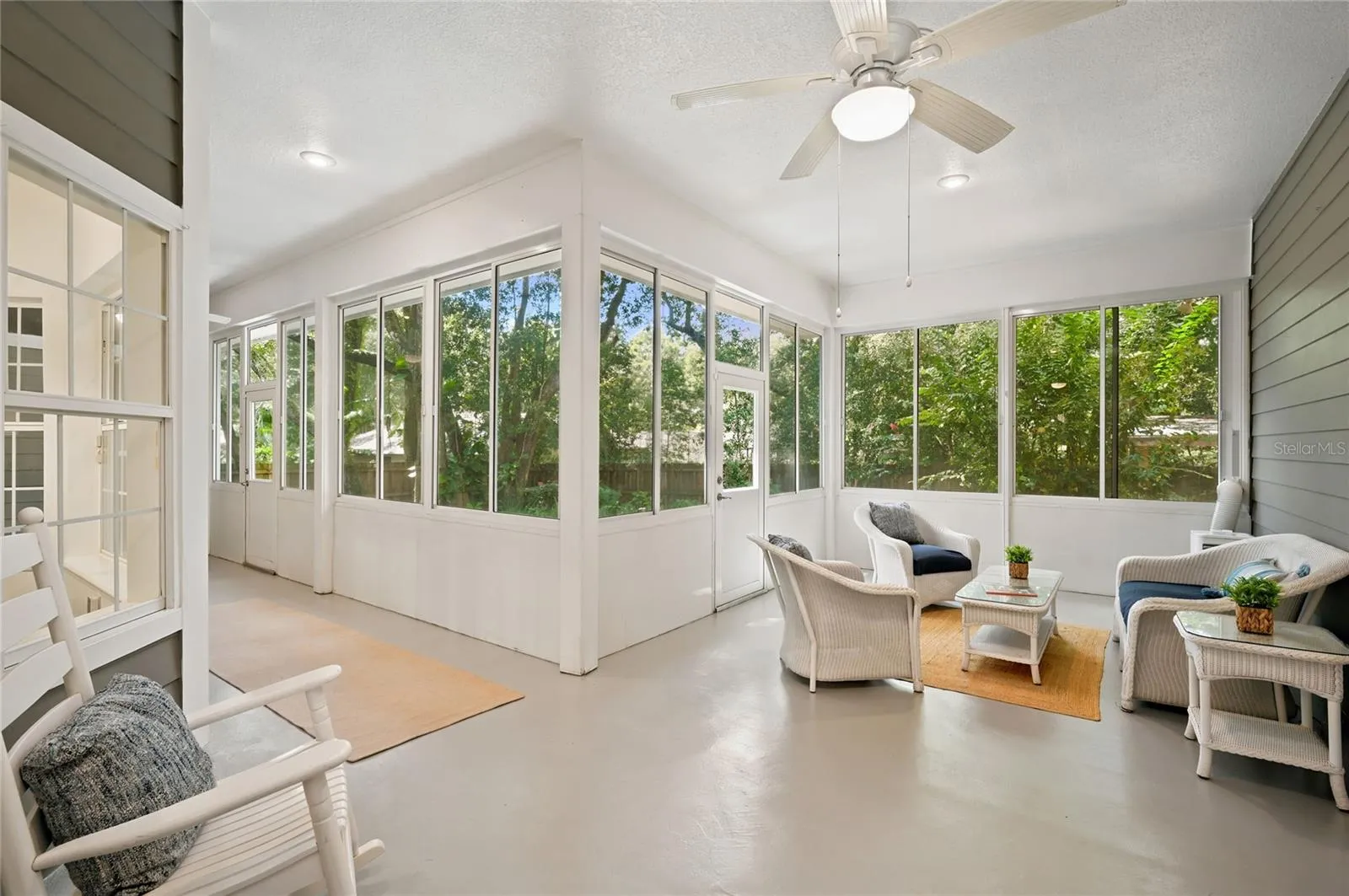 The enclosed porch offers multiple seating areas, ceiling fans, portable A/C and panoramic views of the lush, private backyard.