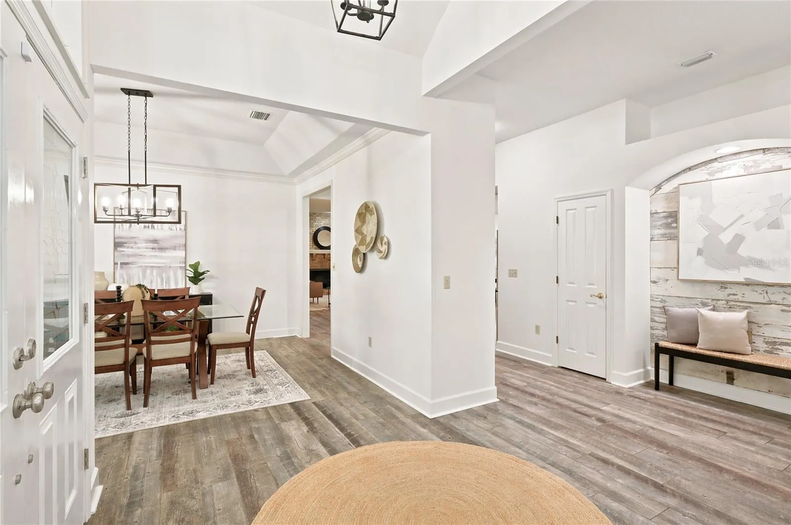A bright, open foyer showcases soaring ceilings, beautiful wood-look flooring, and an elegant formal dining room, creating an inviting introduction to the home.