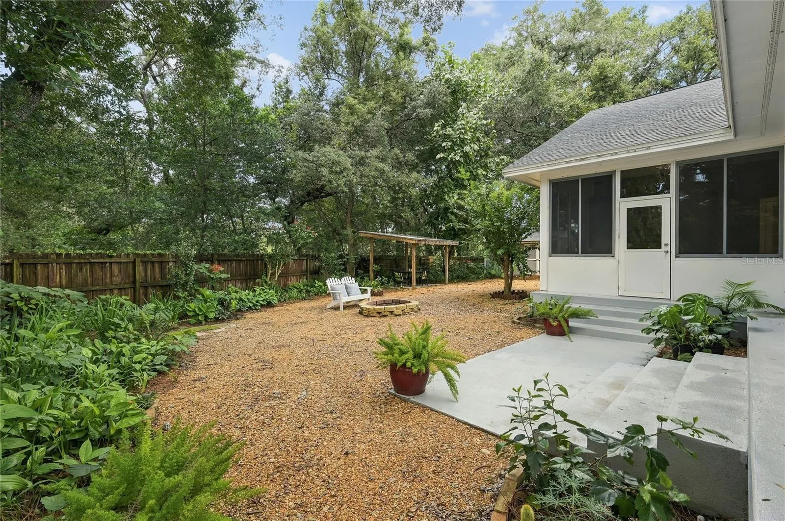 The private, tree-canopied backyard offers a peaceful outdoor retreat surrounded by mature landscaping and lush greenery.