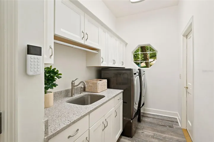 Spacious laundry room features abundant cabinetry, generous counter space, a utility sink, and full-size washer/dryer.