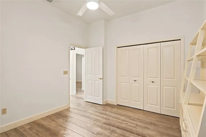 Bedroom 3 offers a comfortable, versatile retreat with high ceilings, wood-look flooring, a ceiling fan, and generous closet space