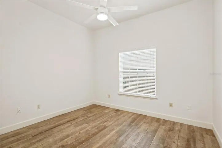Bedroom 4 offers a fresh, airy feel with warm wood-look flooring, a modern ceiling fan, and a well-placed window bringing in natural light.