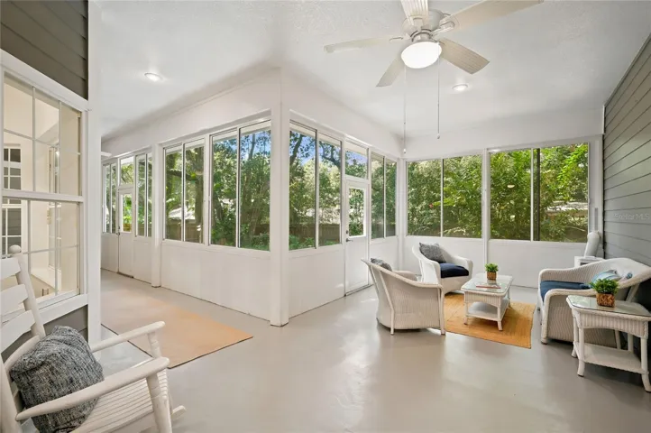 The enclosed porch offers multiple seating areas, ceiling fans, portable A/C and panoramic views of the lush, private backyard.