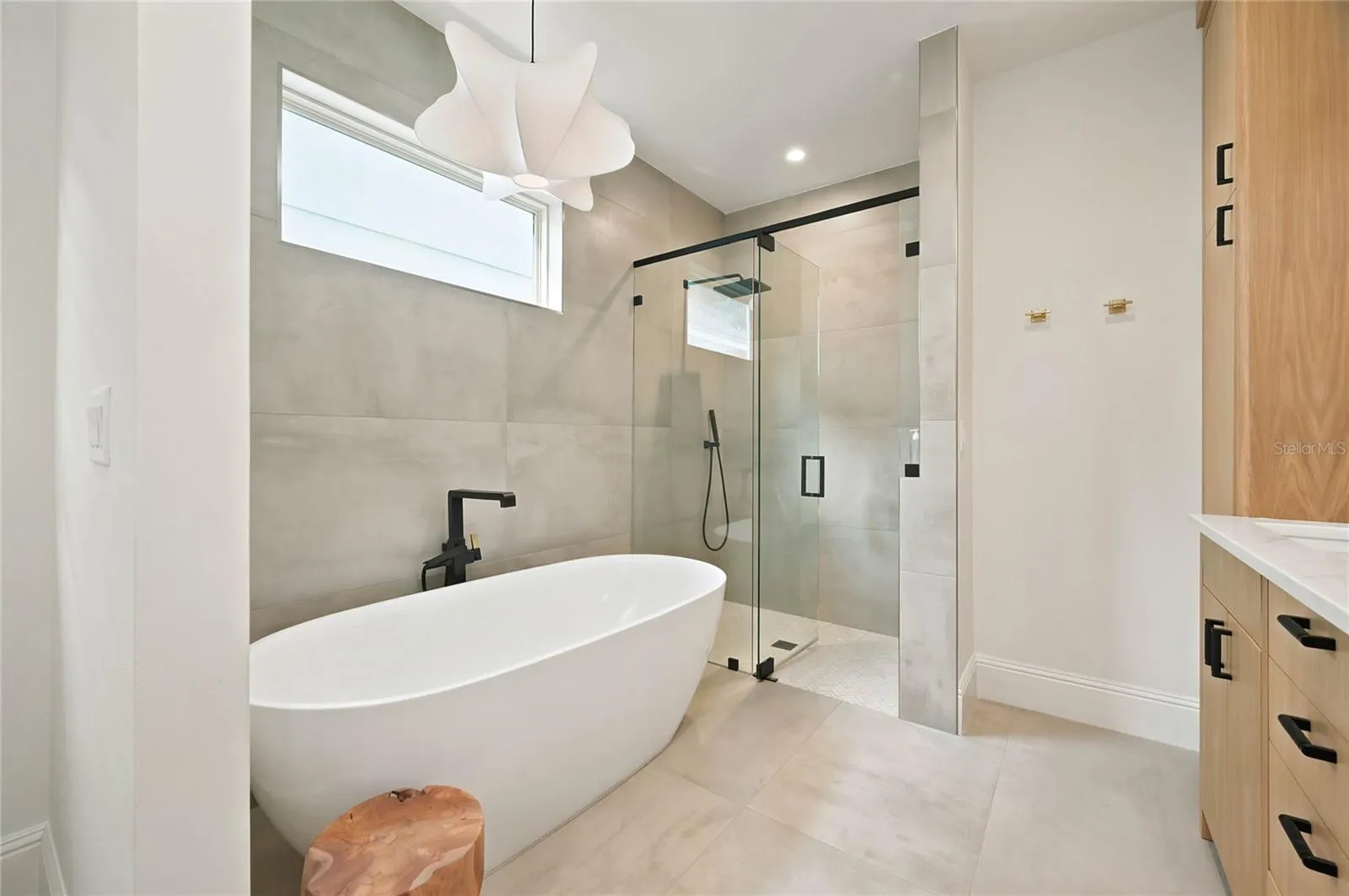 Sculptural soaking tub with bespoke lighting &amp; oversized glass-enclosed shower with additional hand held wand and built in niche