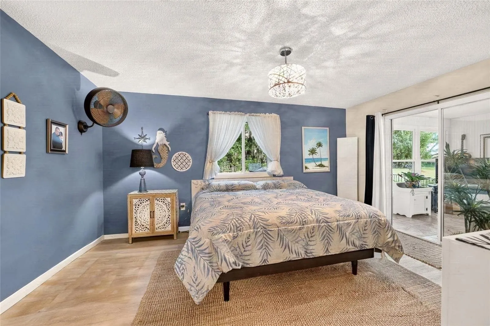 Primary Bedroom with direct access to the Florida room with sliders for light and curtains for privacy. Its the best of both worlds. Private Lot with lots of natural light. A pretty view from every room
