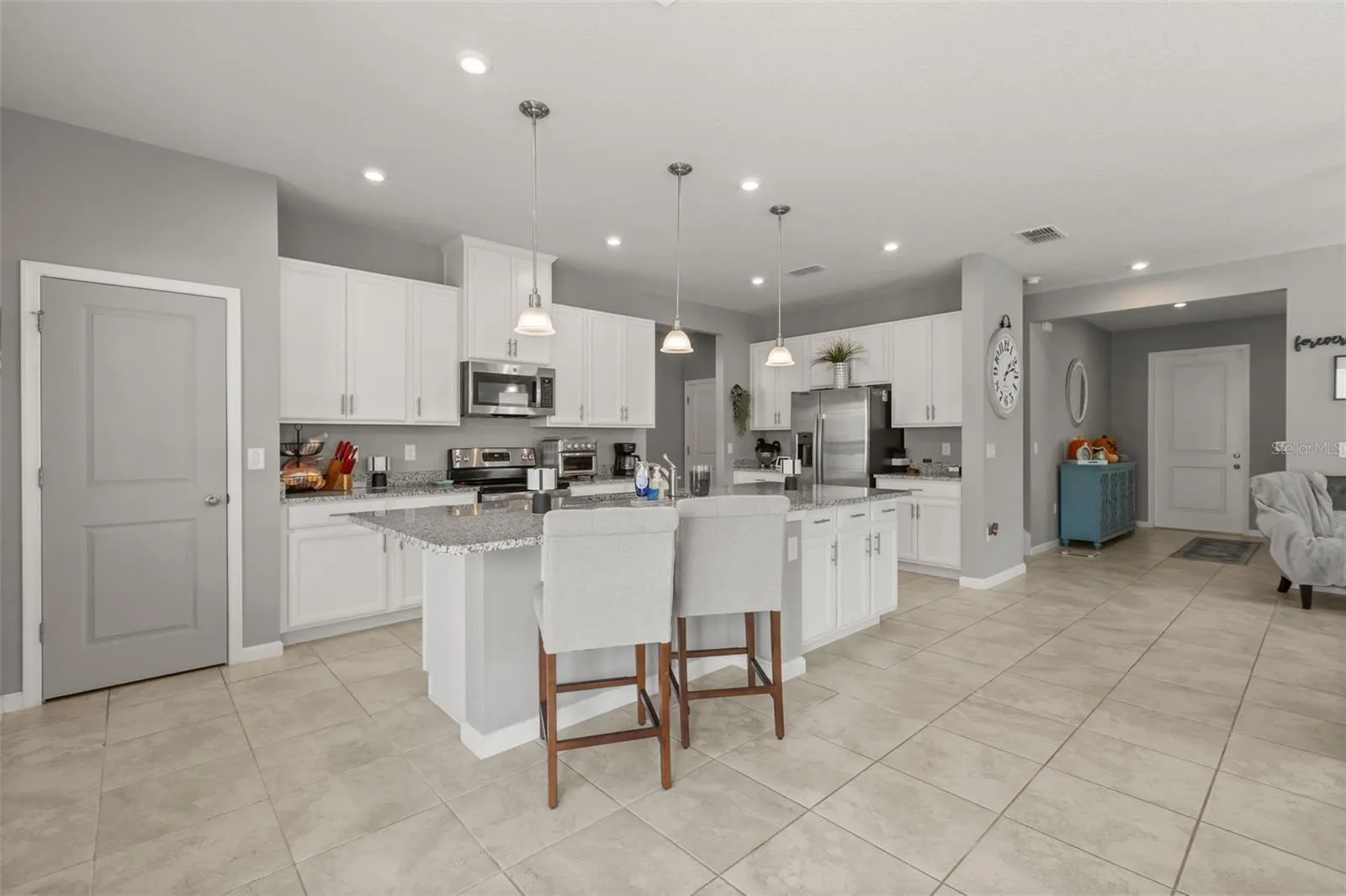 Kitchen area with large granite service island, drop &amp; recessed lighting, and pantry closet