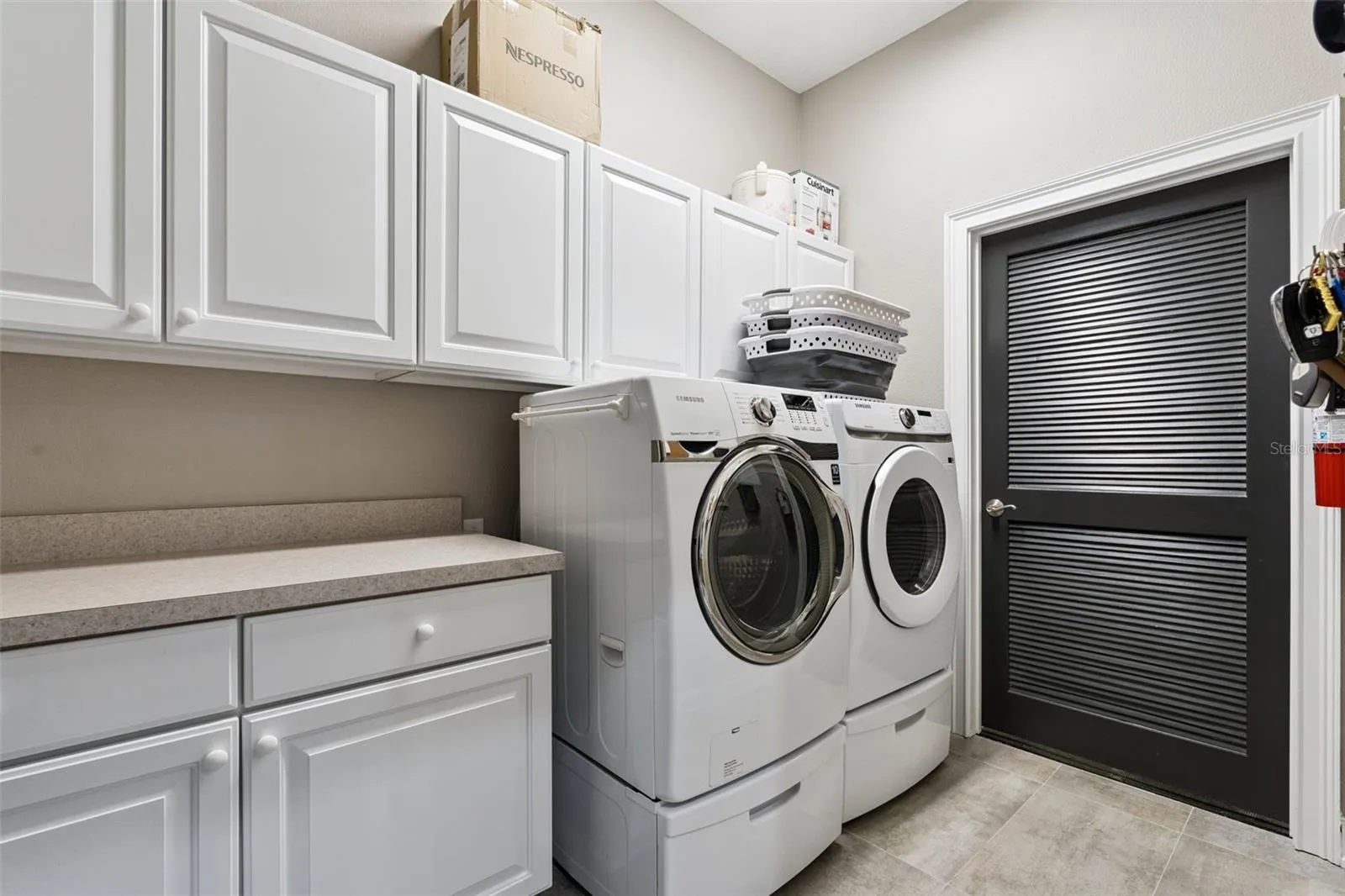 Laundry Room with washer & dryer and door to utility closet with sink, tankless water heater, and storage.