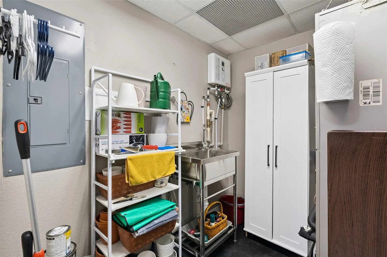 Utility closet with sink and storage.