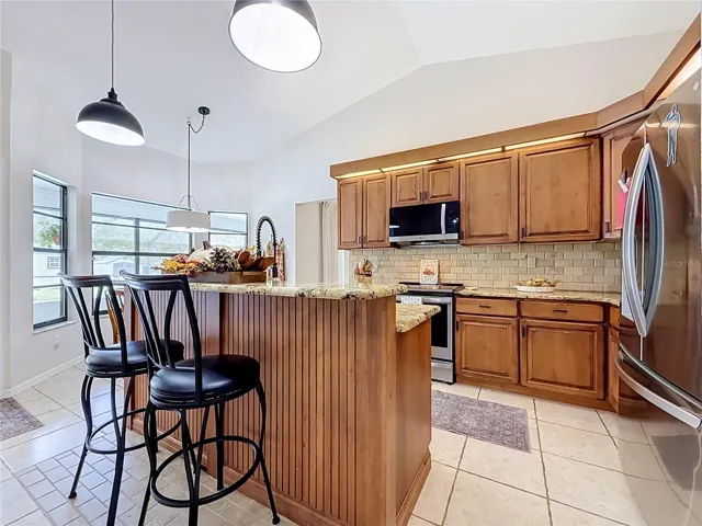 remodeled kitchen with wood cabinets, granite countertops, SS appliances, kitchen island.