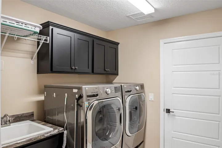 Interior laundry with sink.  Dryer is set up for gas or electric connection.  Extra Storage above washer and dryer.